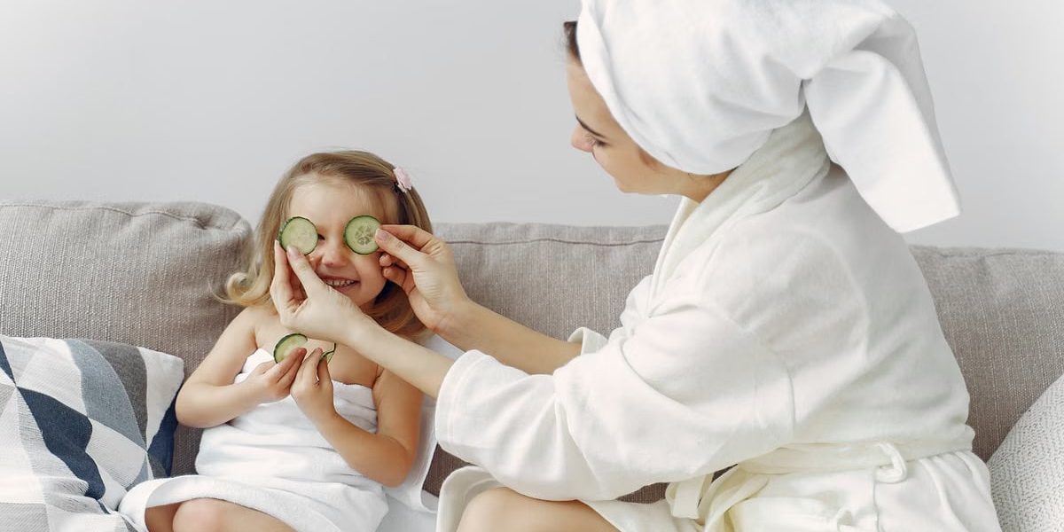 A mother and daughter enjoy a relaxing spa day at home with cucumbers and laughter.