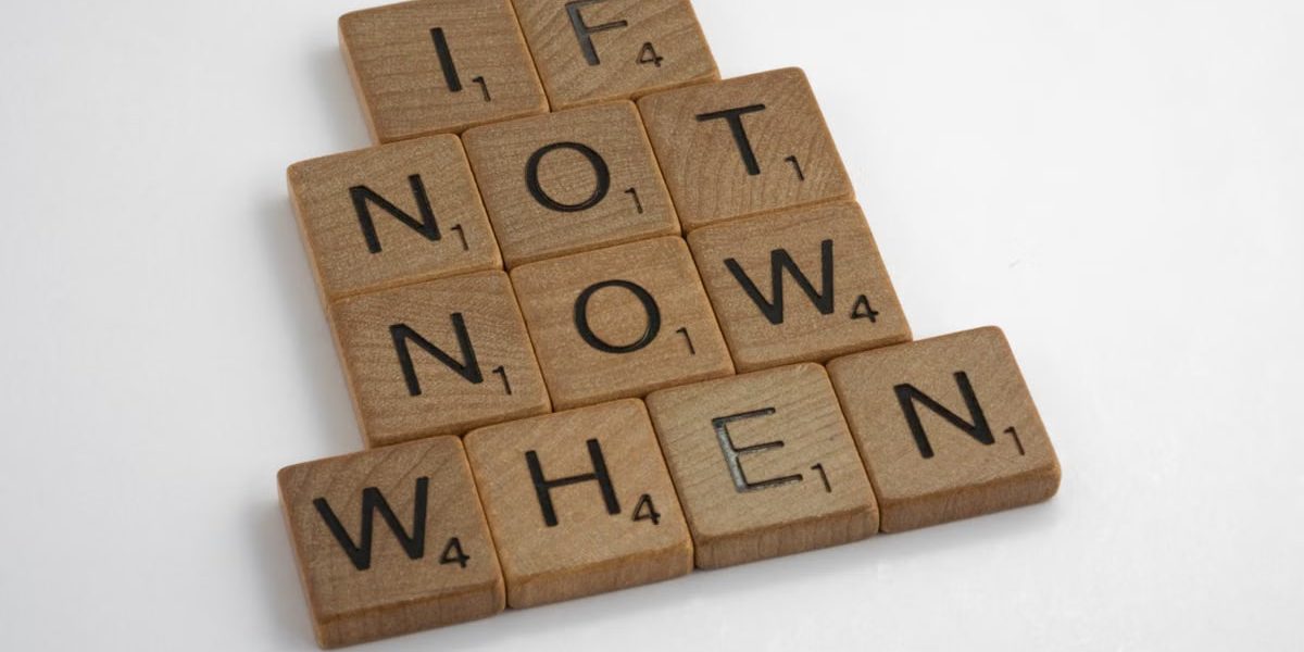 Wooden letter tiles spelling 'If Not Now When' on a white background for inspiration.